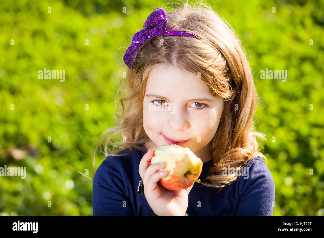 happy kid eating fruits from picnic basket sitting on the green grass Stock Photo