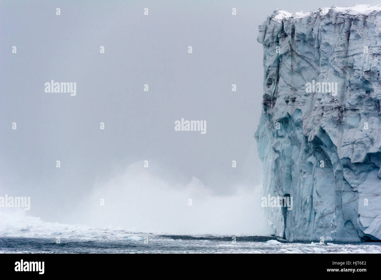 Ice collapses from the fracture zone of a glacier into the ocean. Stock Photo