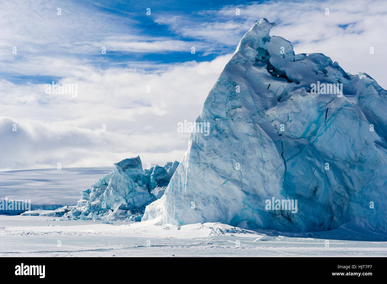 An enormous jagged iceberg trapped in frozen sea ice. Stock Photo