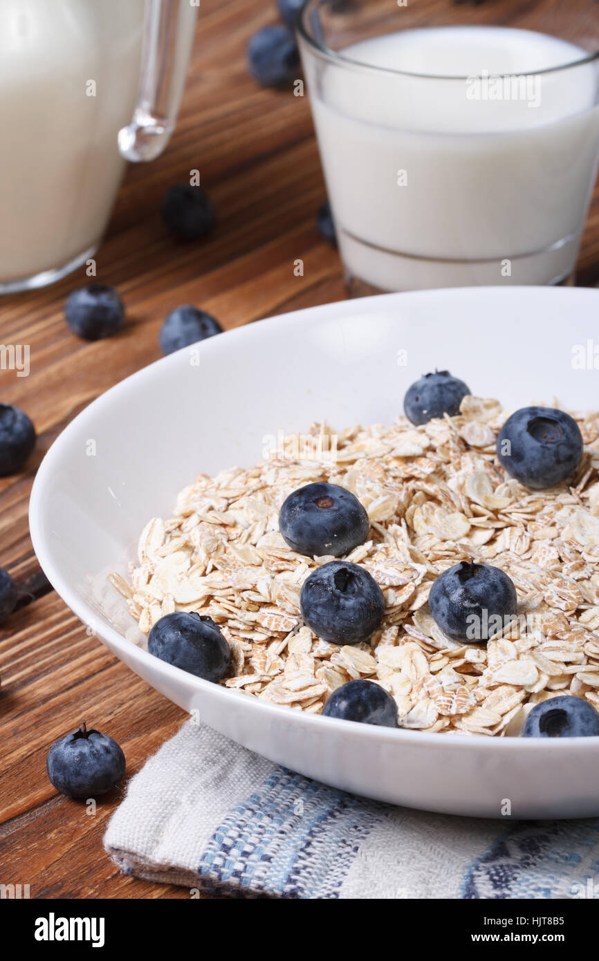 Oatmeal with blueberries and milk in a glass on the table close-up vertical Stock Photo