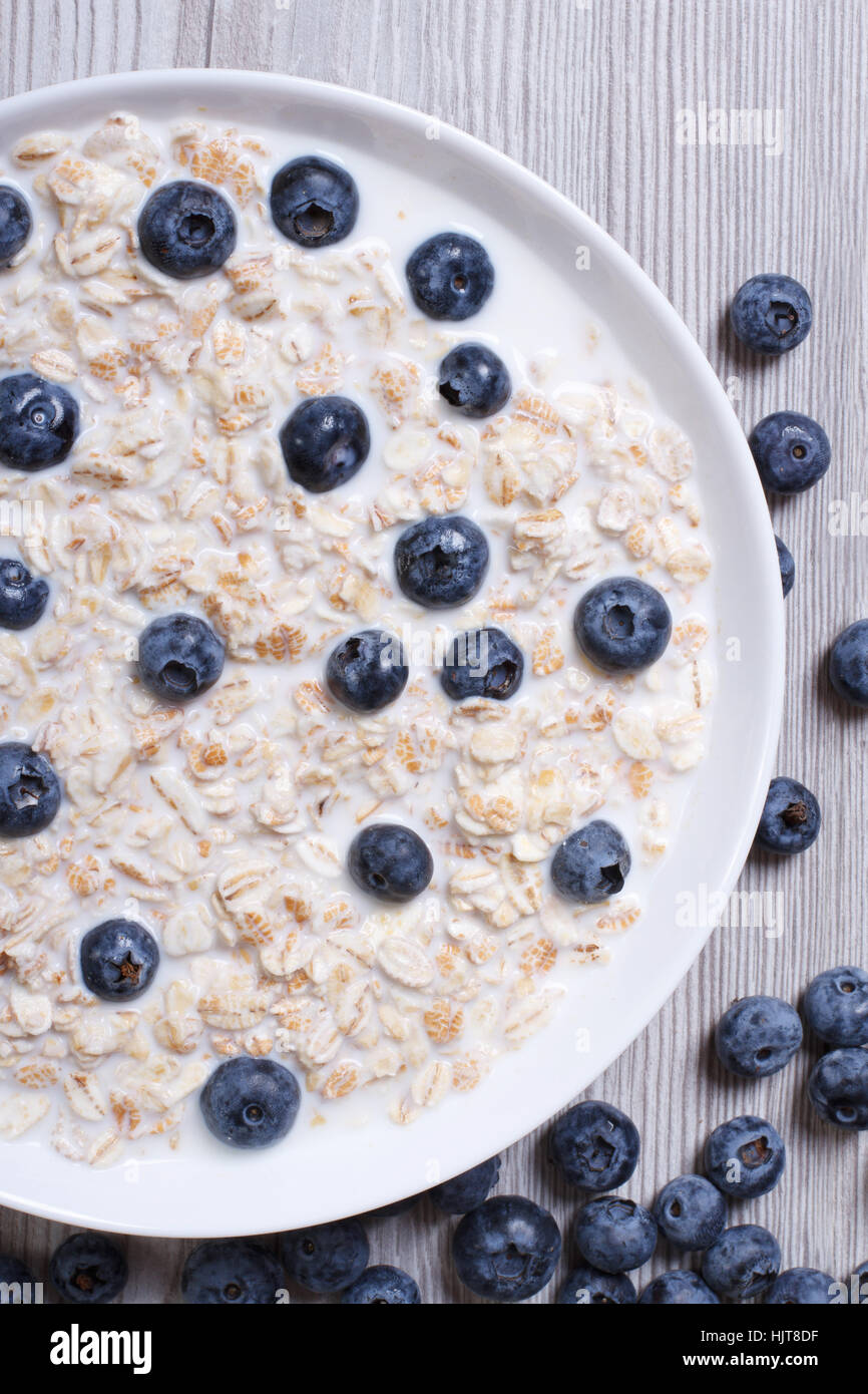 A healthy breakfast of oatmeal with blueberries and milk closeup on wooden background. top view vertical Stock Photo