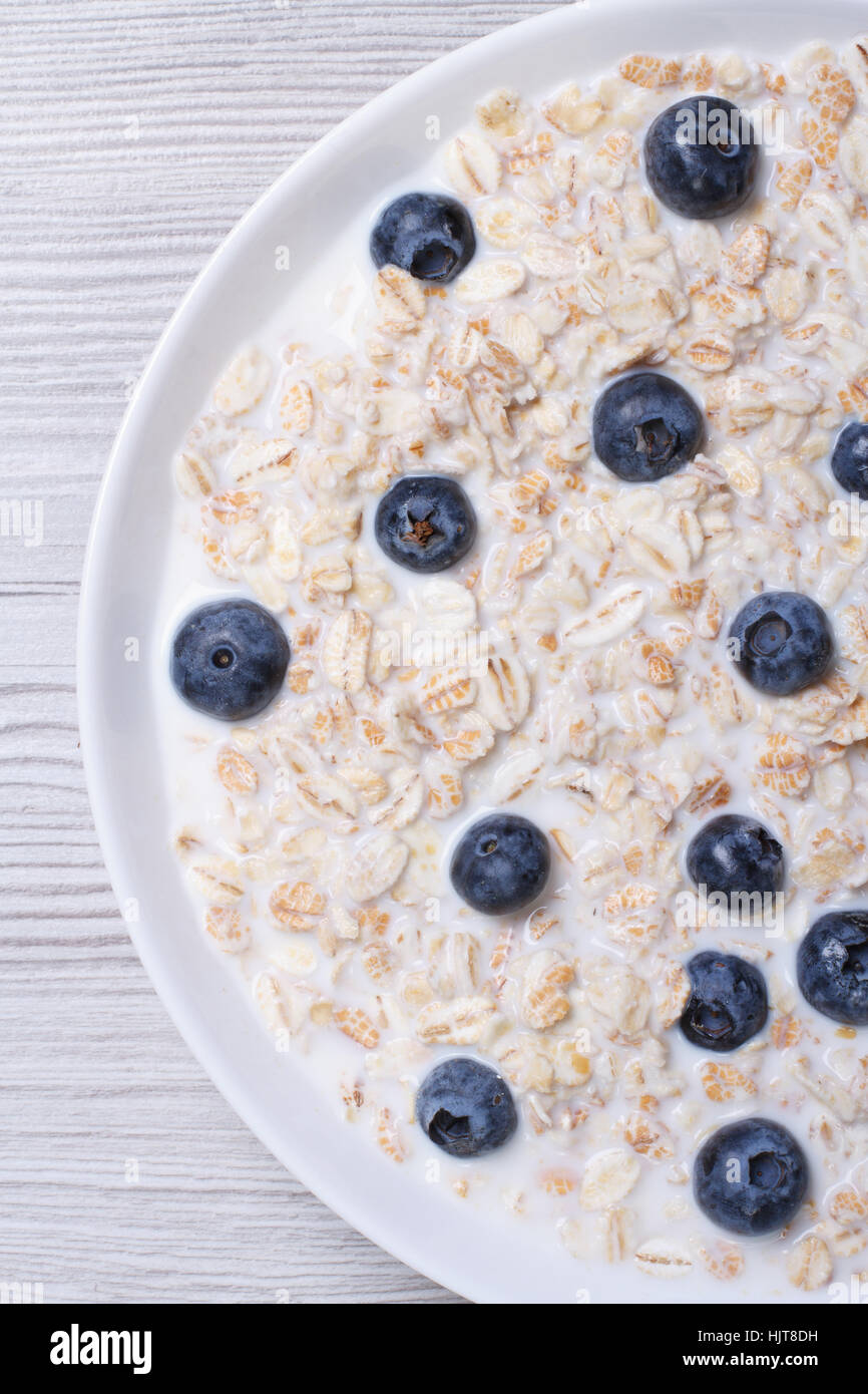 oatmeal with milk and blueberries closeup on wooden background. top view vertical Stock Photo