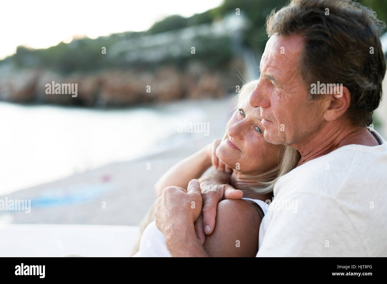 Senior couple relaxing together on the beach at evening twilight Stock ...