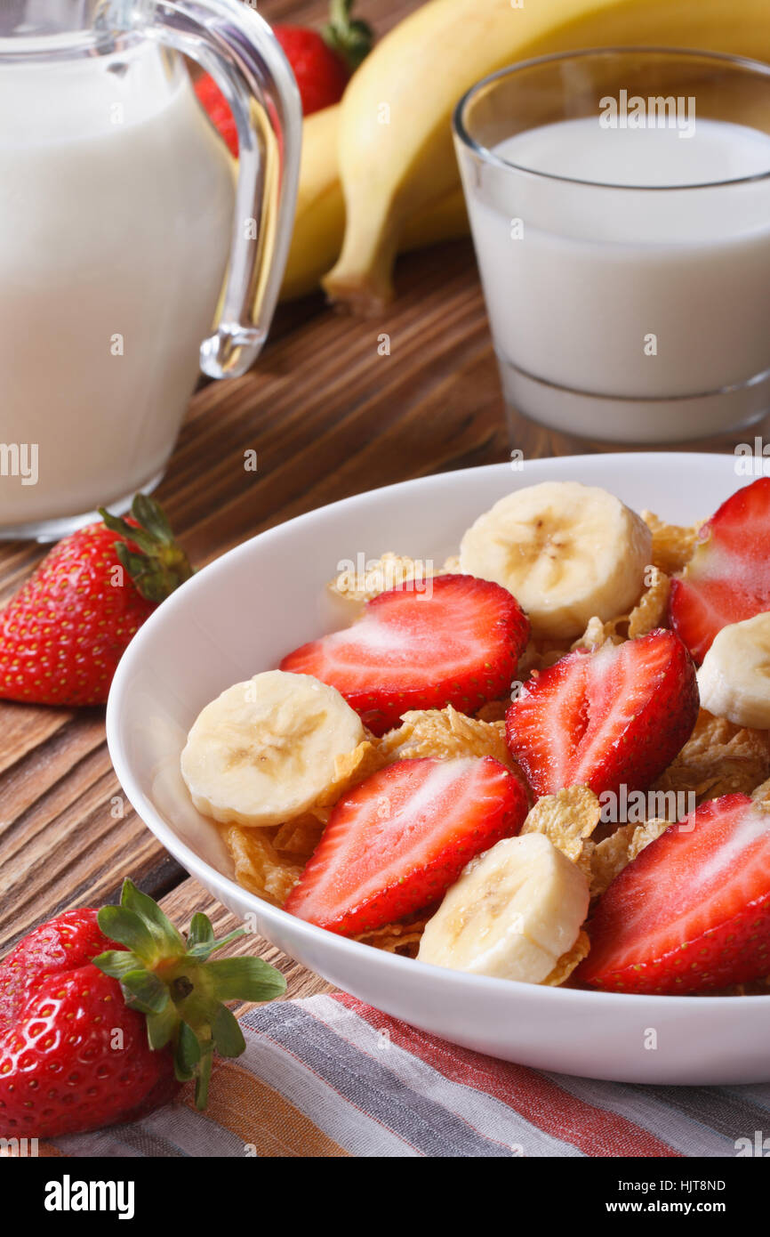 Cornflakes with strawberries, banana and milk on the table close-up vertical Stock Photo