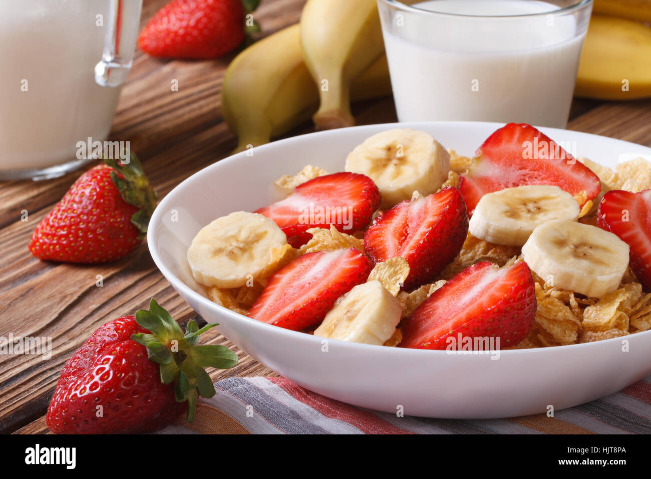 Muesli with fresh strawberries and a banana on the table and milk in a jug. horizontal Stock Photo
