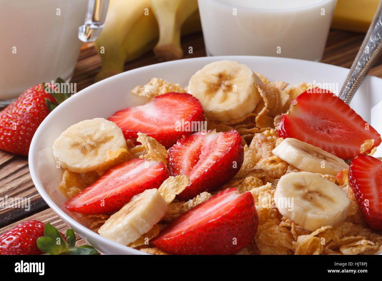corn muesli with fresh strawberries and banana close up on the table and milk. horizontal Stock Photo