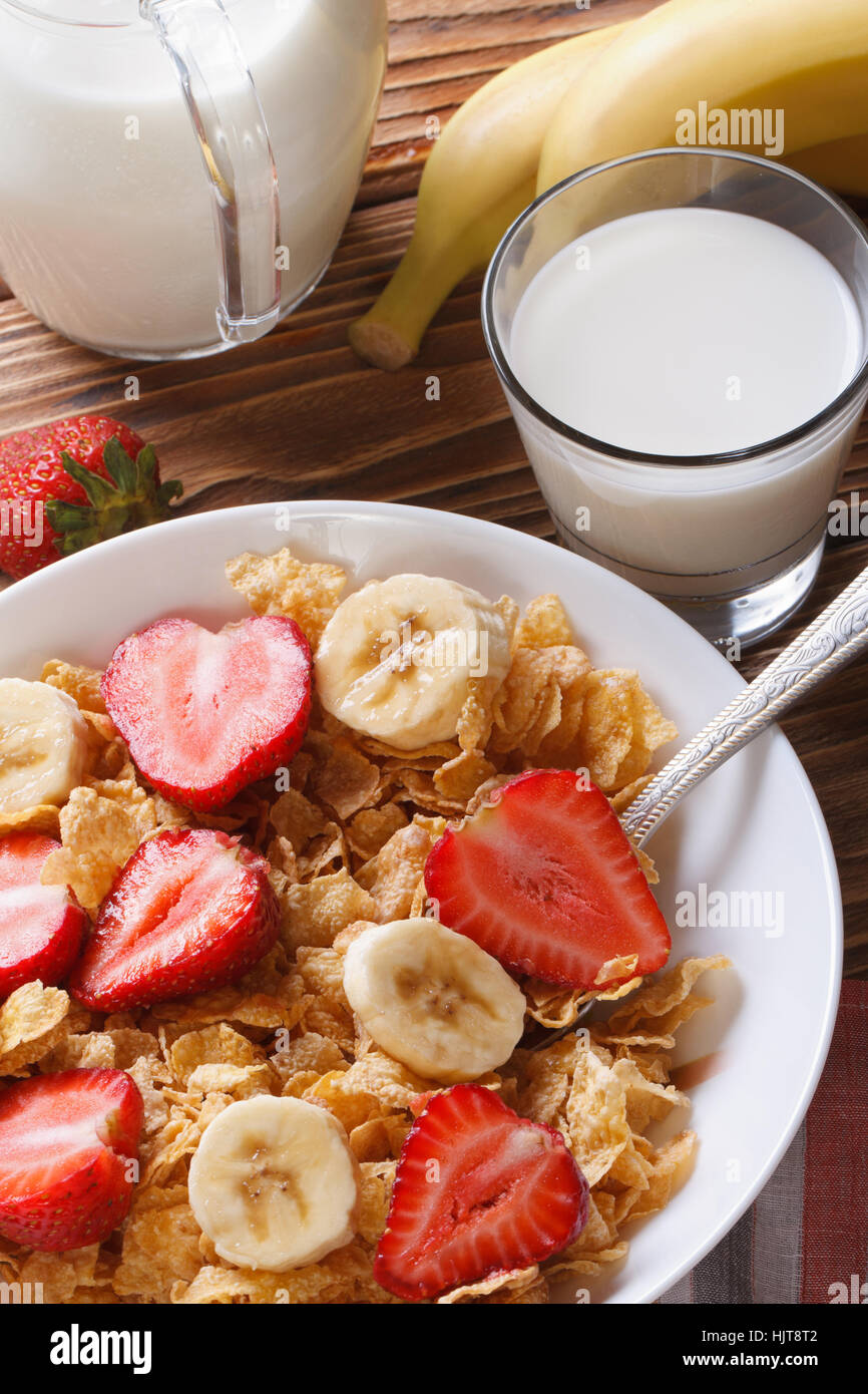 corn muesli with fresh strawberries and banana close up on the table and milk. vertical view from above Stock Photo
