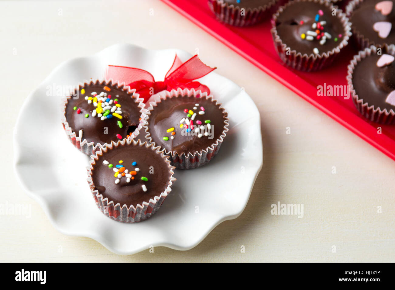 chocolate candies with colorful sprinkles on a white plate Stock Photo