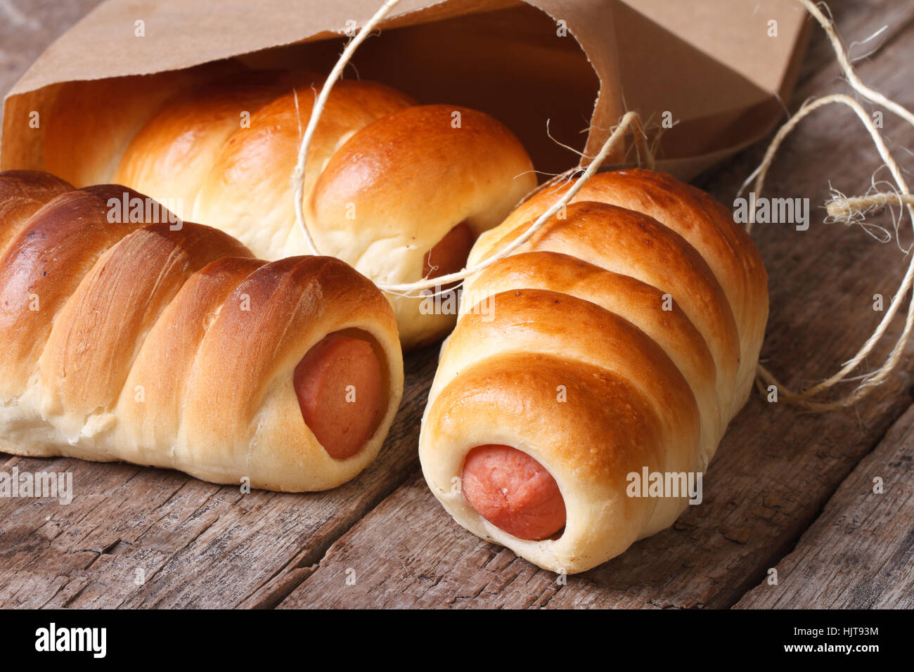 rolls with sausage closeup unpacked paper on wooden table horizontal Stock Photo