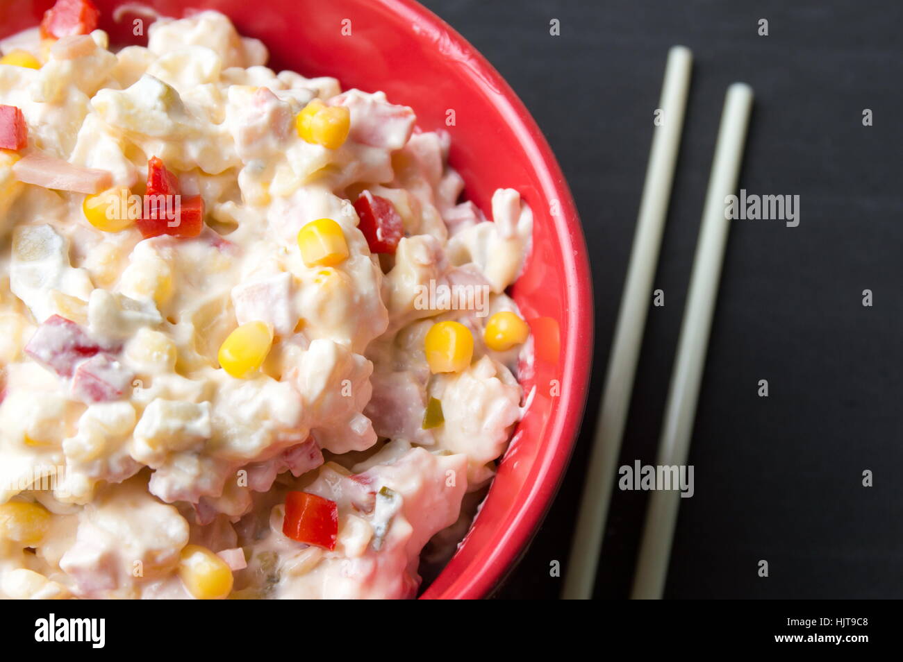 mixed vegetable and mayo salad in a red bowl with chopsticks Stock