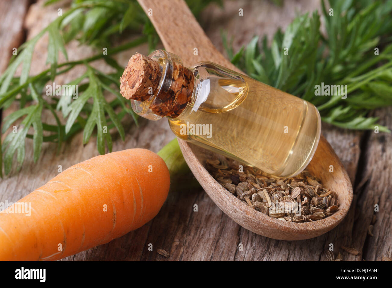 Useful carrot seed oil in glass bottle on the table close-up horizontal. Stock Photo