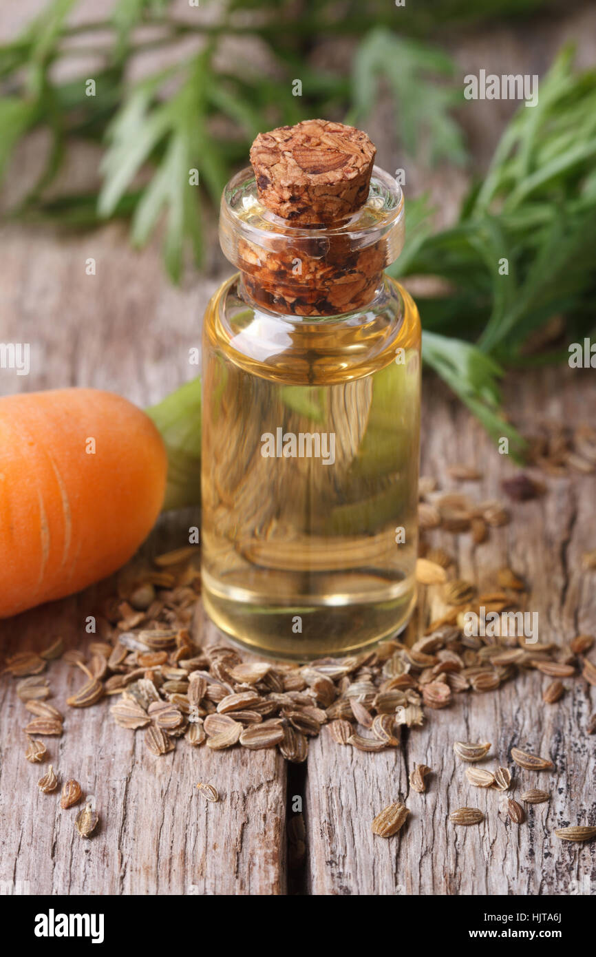 Medicated oil of carrot seeds in a glass bottle on the table close-up vertical Stock Photo