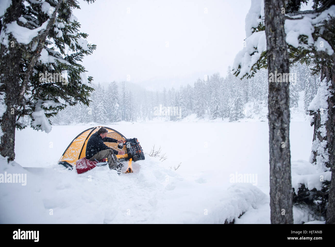 Senior man camping in snow-covered landscape Stock Photo