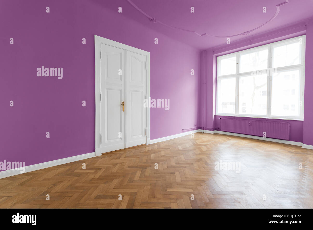 violet walls, pink room with wooden parquet floor - empty apartment room in   restored old building Stock Photo
