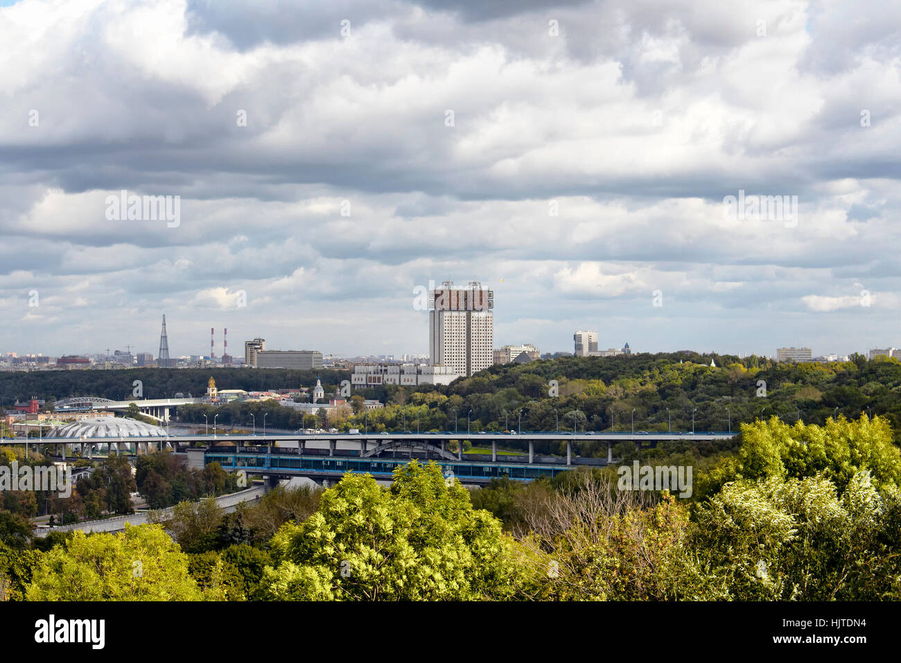 View of Russian Academy of Sciences building from the observation deck at Sparrow hills in Moscow. Trees, Moskva river and dramatic clouds are in the  Stock Photo