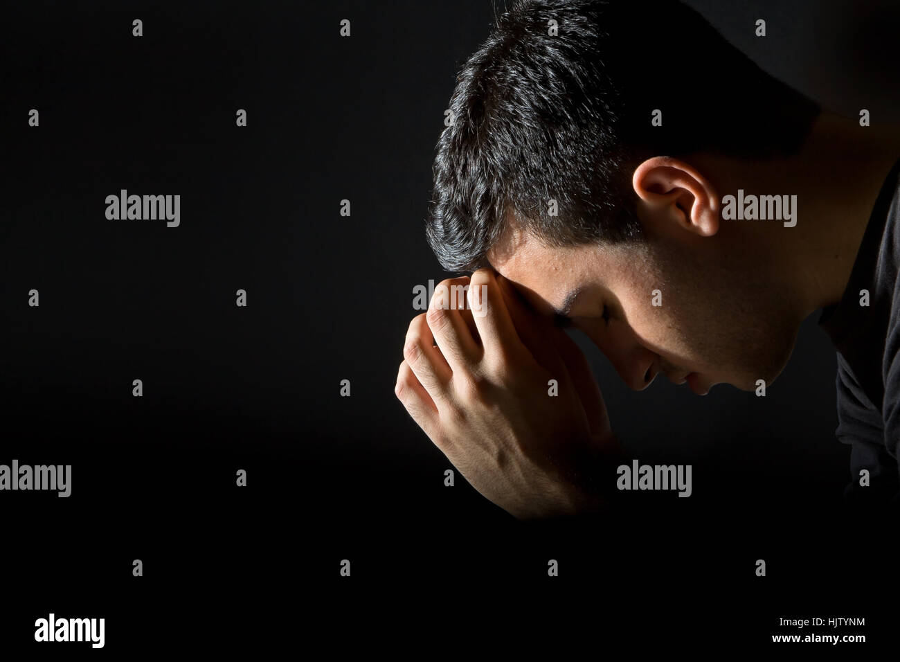 Young man praying in the dark Stock Photo Alamy