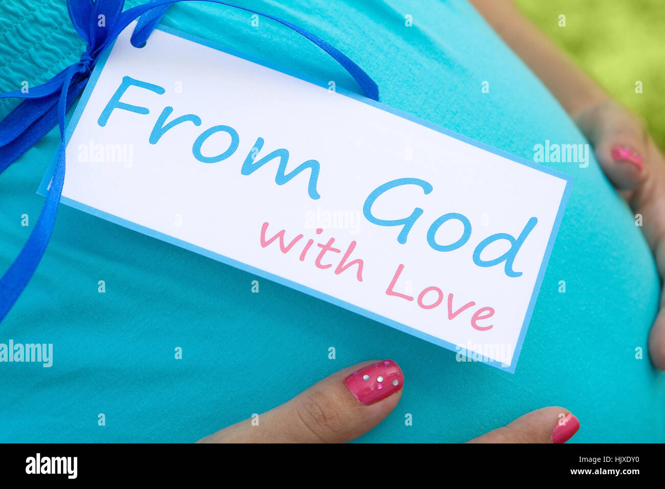 Close-up of expecting mom's tummy with card 'From God with Love' Stock Photo