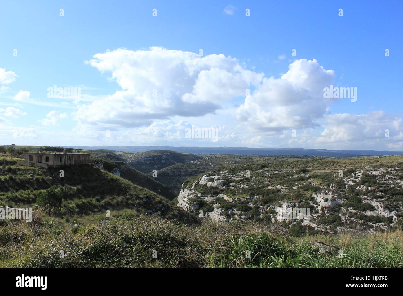 Cumulonimbus clouds float in a blue sky over the rolling hills of Sicily. Stock Photo