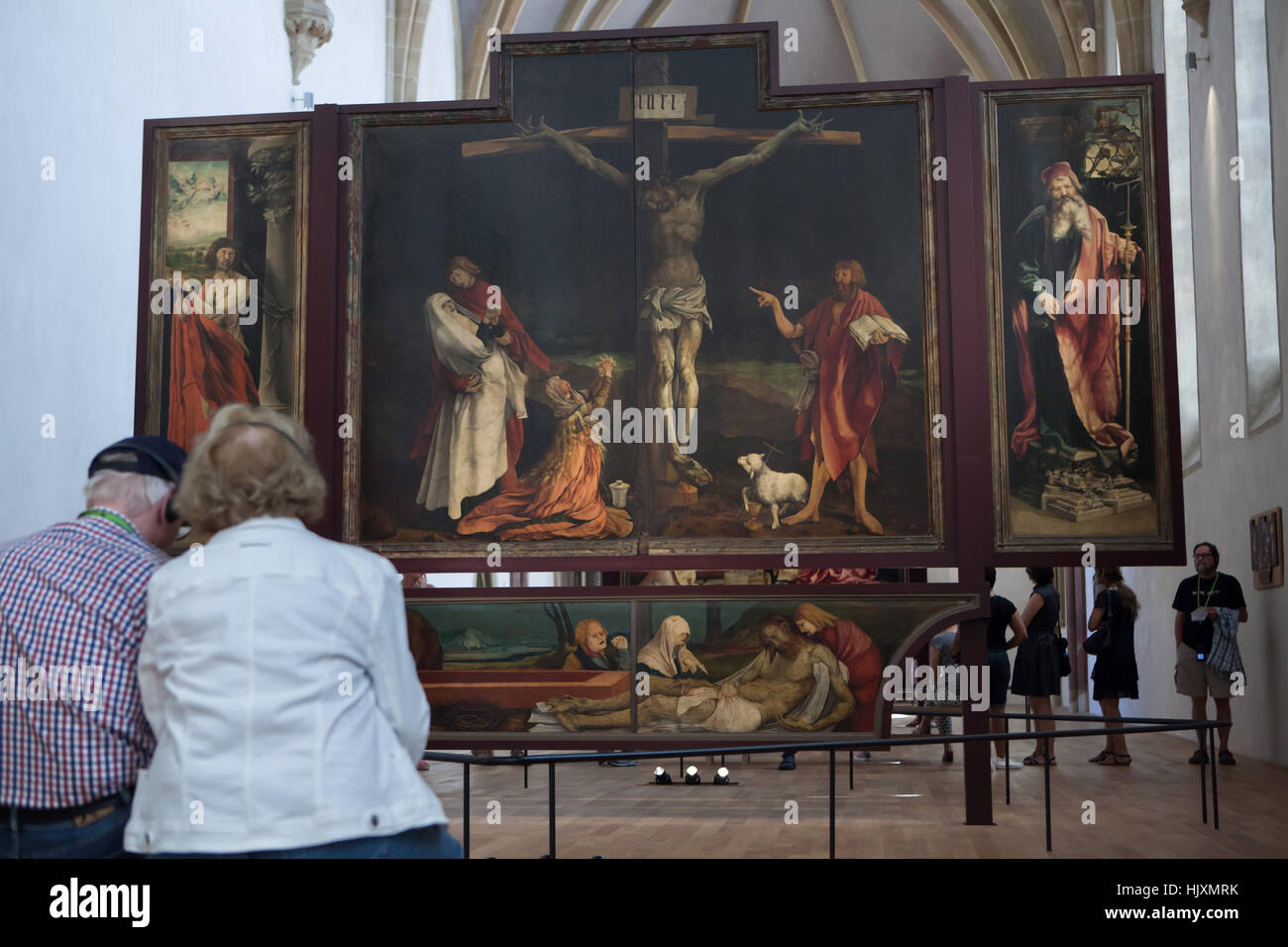 Visitors in front of the Isenheim Altarpiece (1512–1516) by German Renaissance painter Matthias Grunewald displayed in the Musee d'Unterlinden (Unterlinden Museum) in Colmar, Alsace, France. First view of the Isenheim Altarpiece with Crucifixion framed by the martyrdom of Saint Sebastian on the left, and by Saint Anthony the Great on the right. Stock Photo