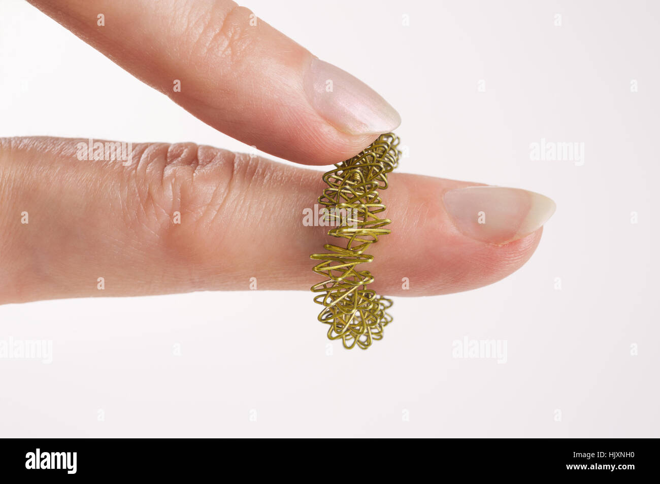 Woman's fingers with golden Sujok Massager Ring  on white background Stock Photo