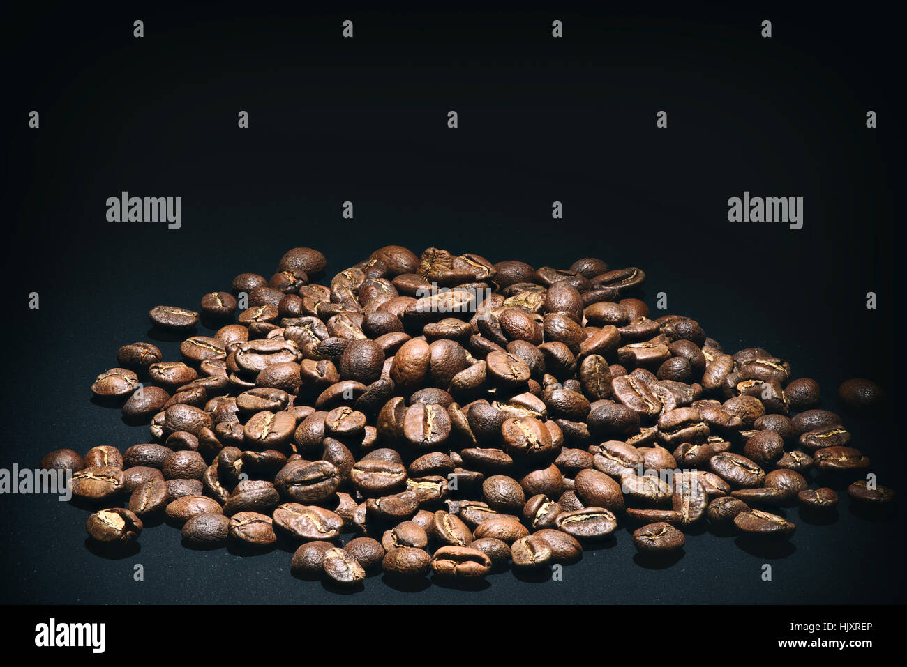heap of fresh coffee beans on black background Stock Photo - Alamy