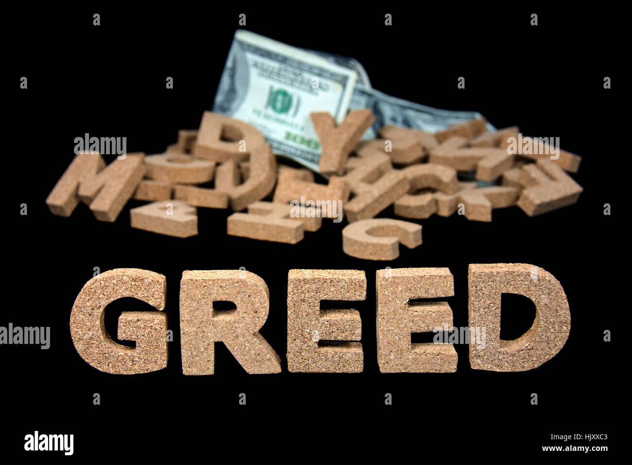 word greed in block cork letters and money in pile of jumbled alphabet letters Stock Photo