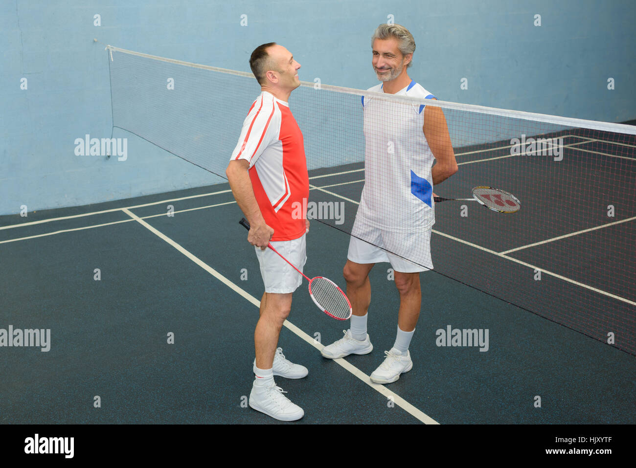 Men chatting over badminton net Stock Photo - Alamy