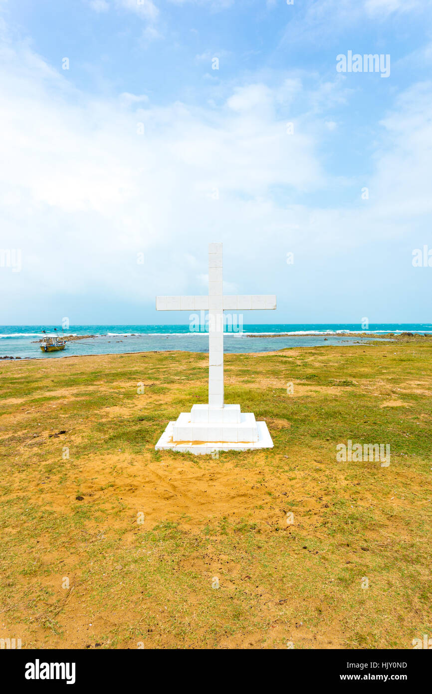 White cross is planted outside of Saint Thomas Church along the ocean in Point Pedro, Jaffna, Sri Lanka. Vertical Stock Photo