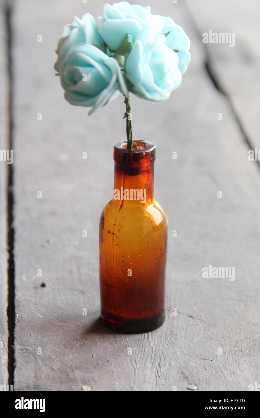 blue roses in a brown glass bottle Stock Photo