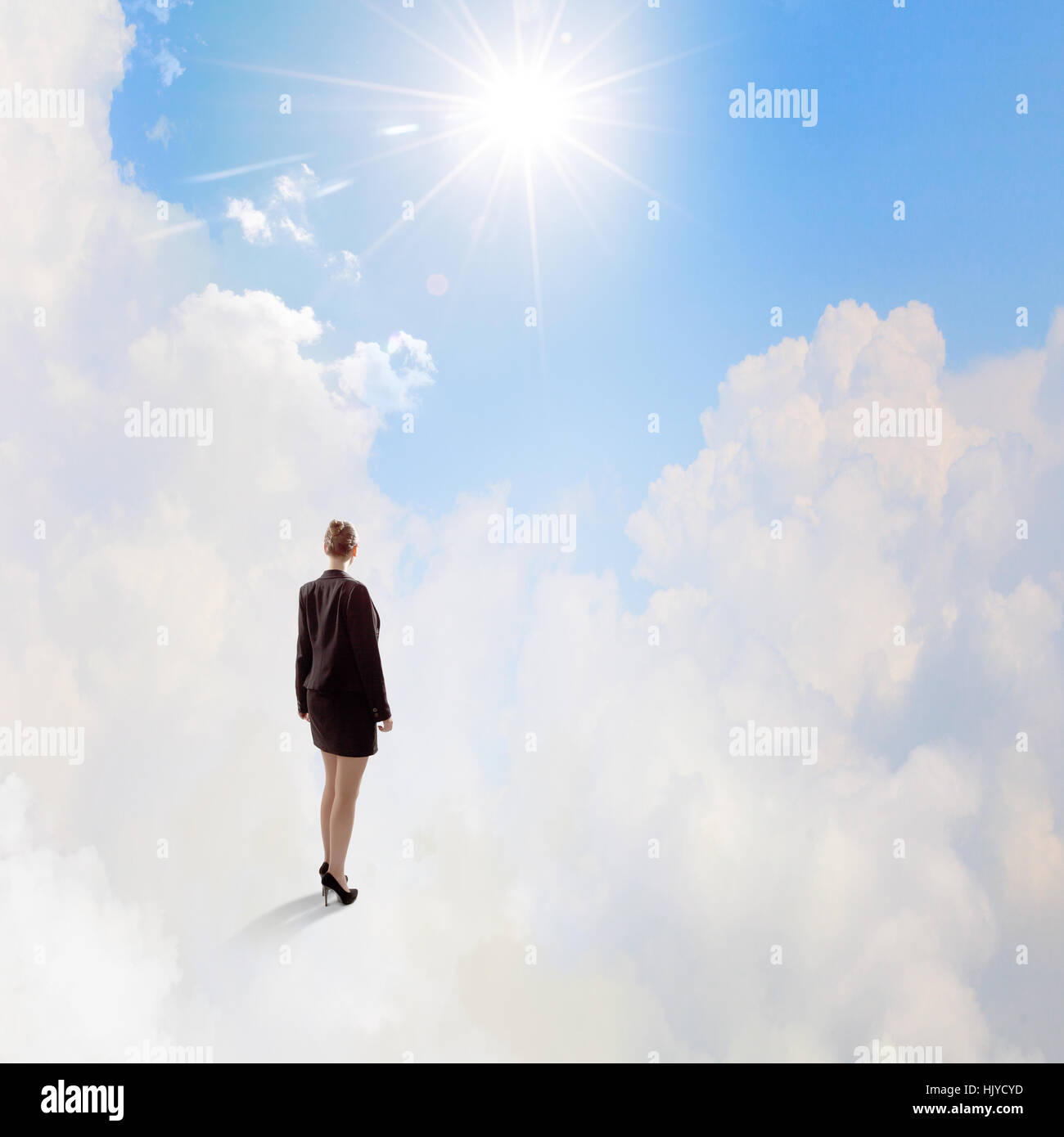 Rear view of businesswoman standing on cloud high in sky Stock Photo ...
