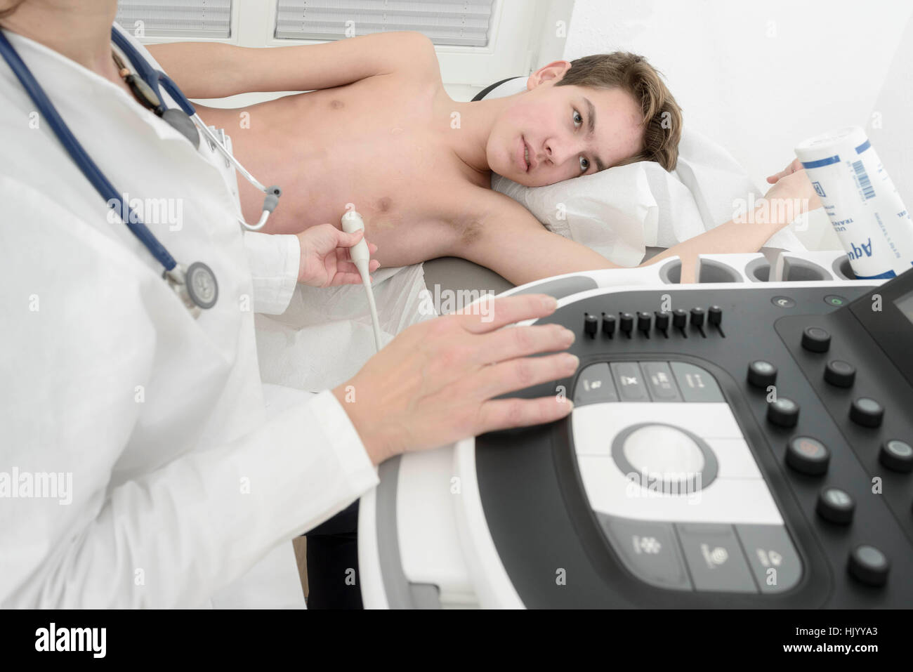 Female cardiologist performs echocardiogram of the heart on  teenage boy Stock Photo