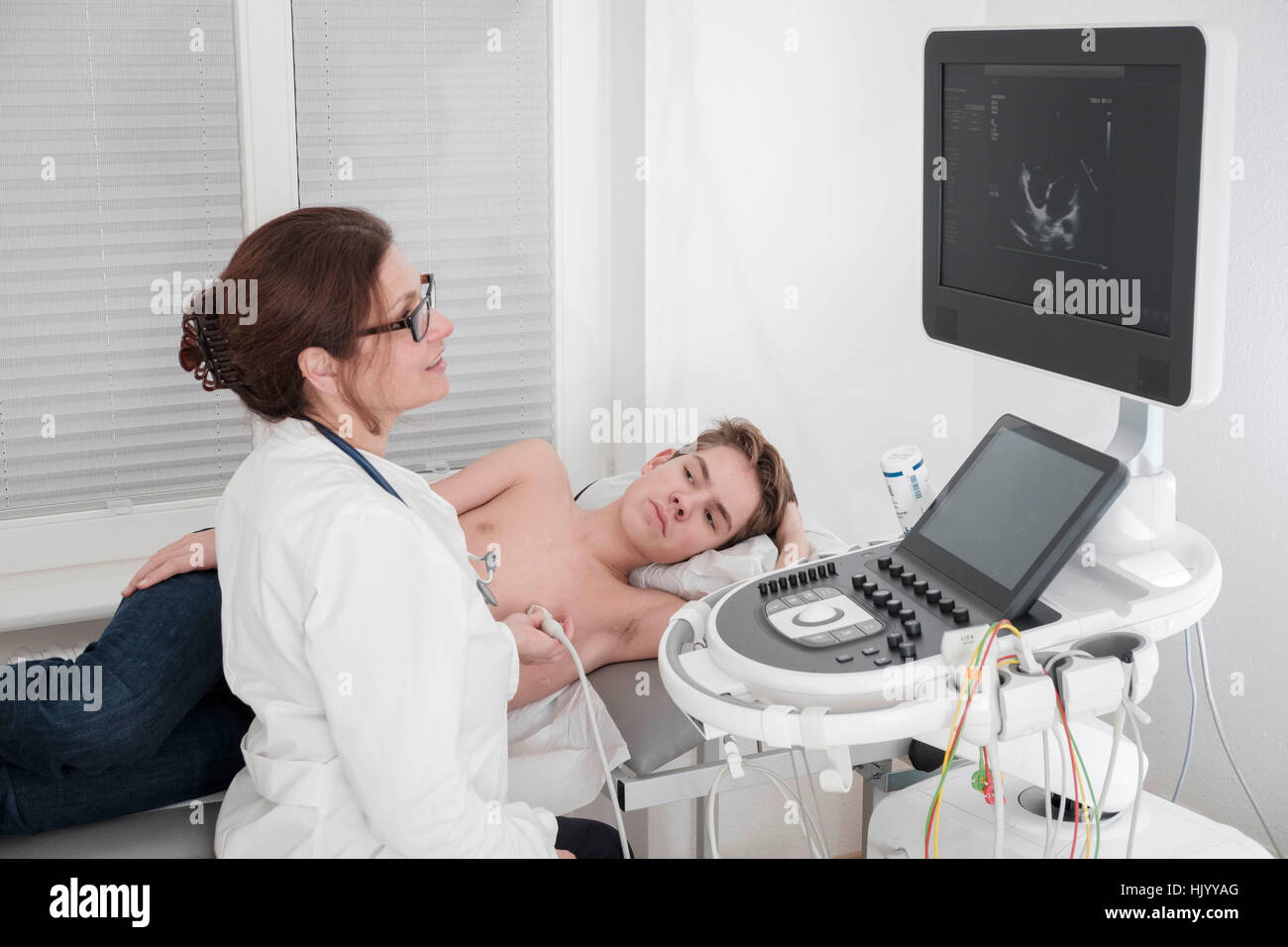 Cardiologist performs echocardiogram of the heart on  teenage boy Stock Photo