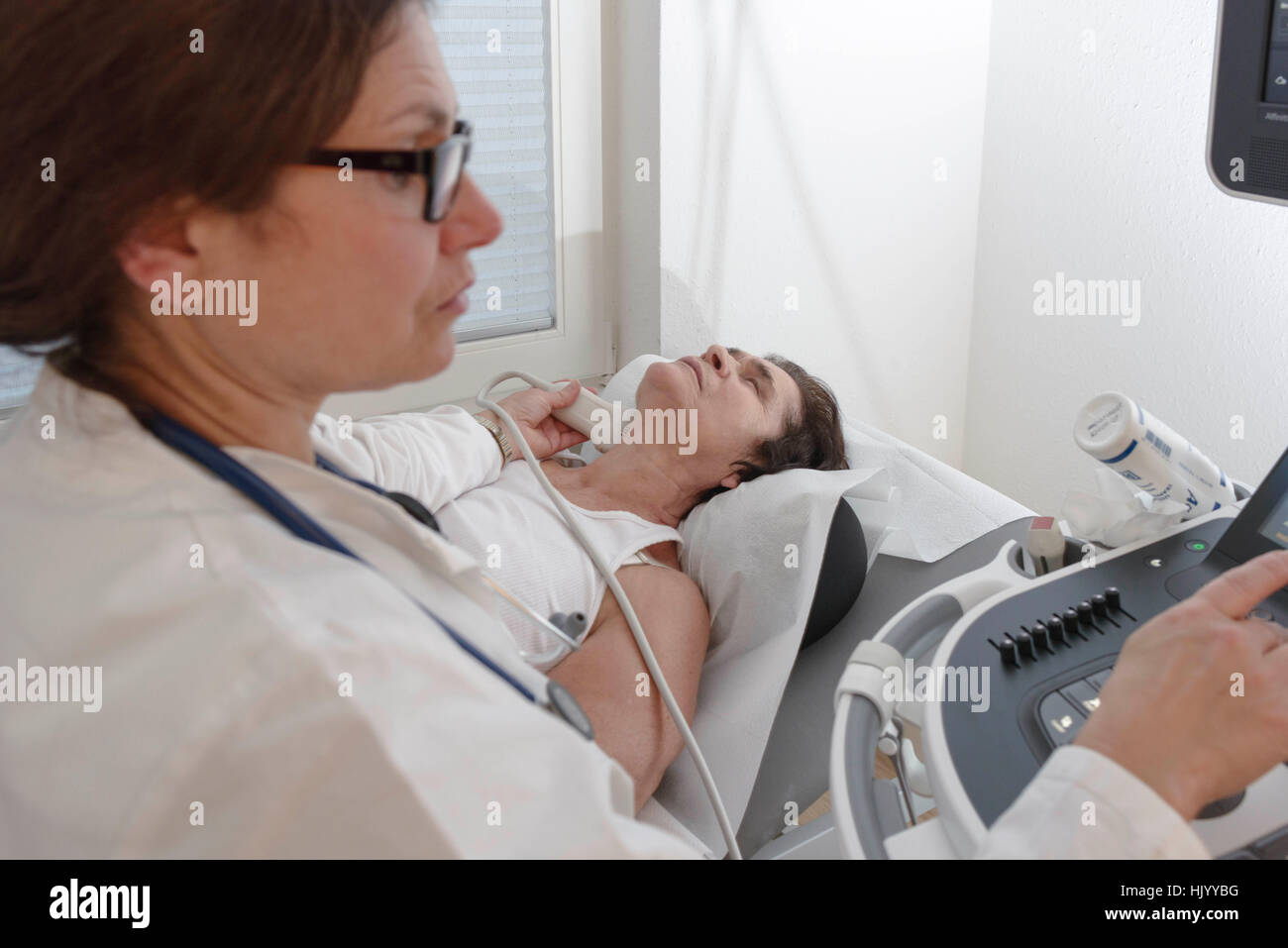 Doctor checking thyroid gland on senior female patient Stock Photo