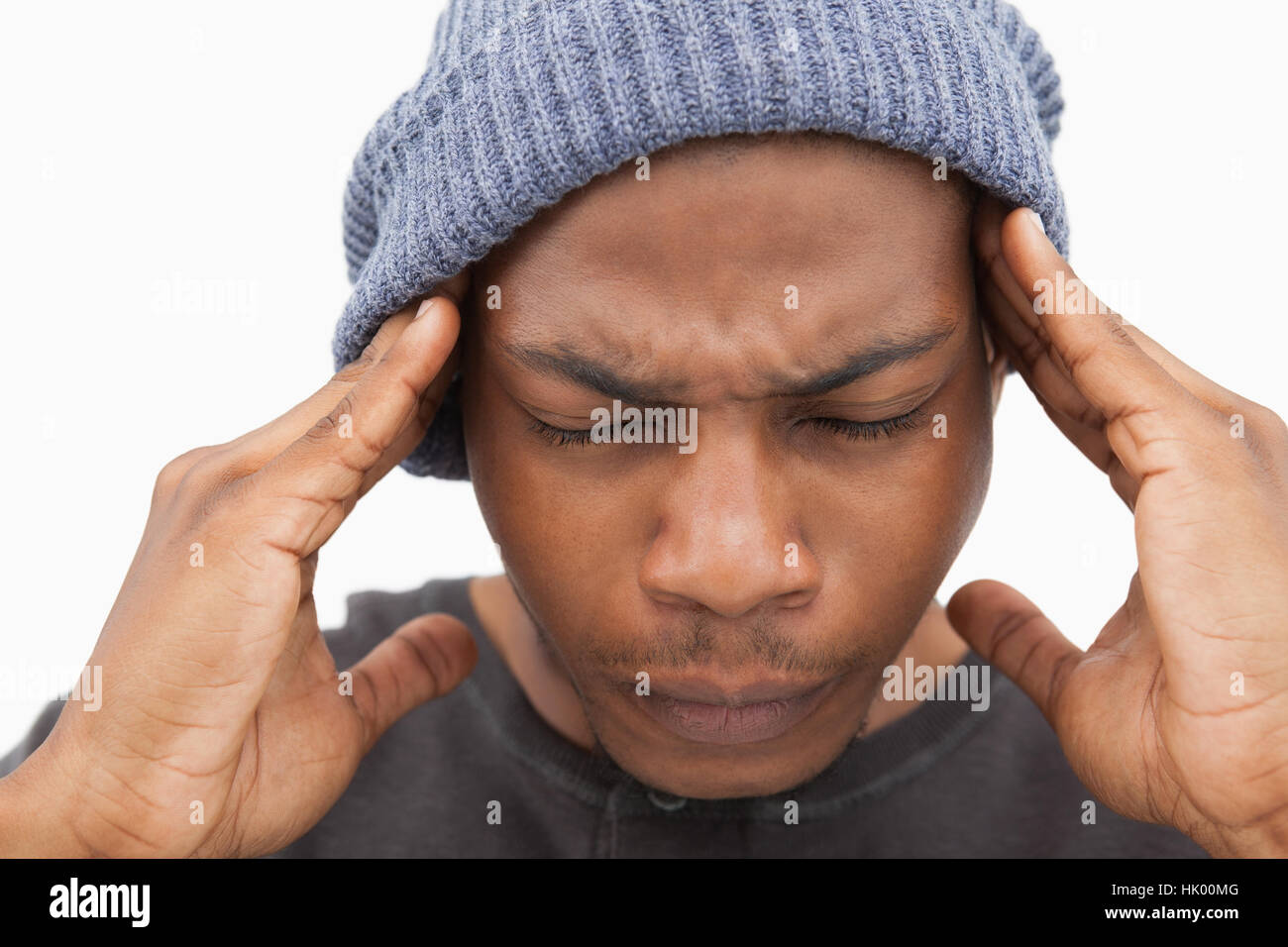 Man in beanie hat grimacing with pain of headache on white background