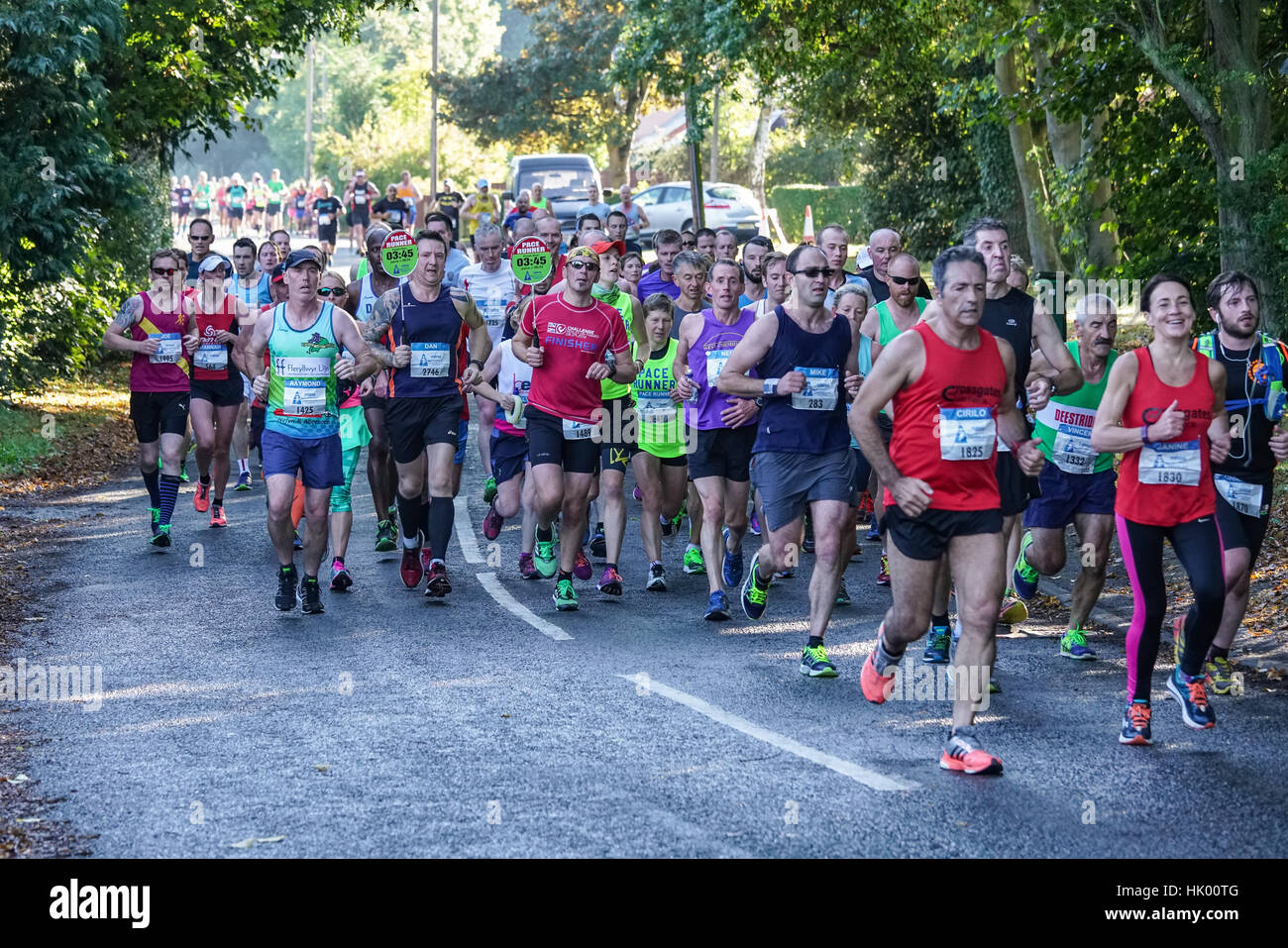 A group of runners in the Chester Marathon crowd round the pace runners Stock Photo Alamy