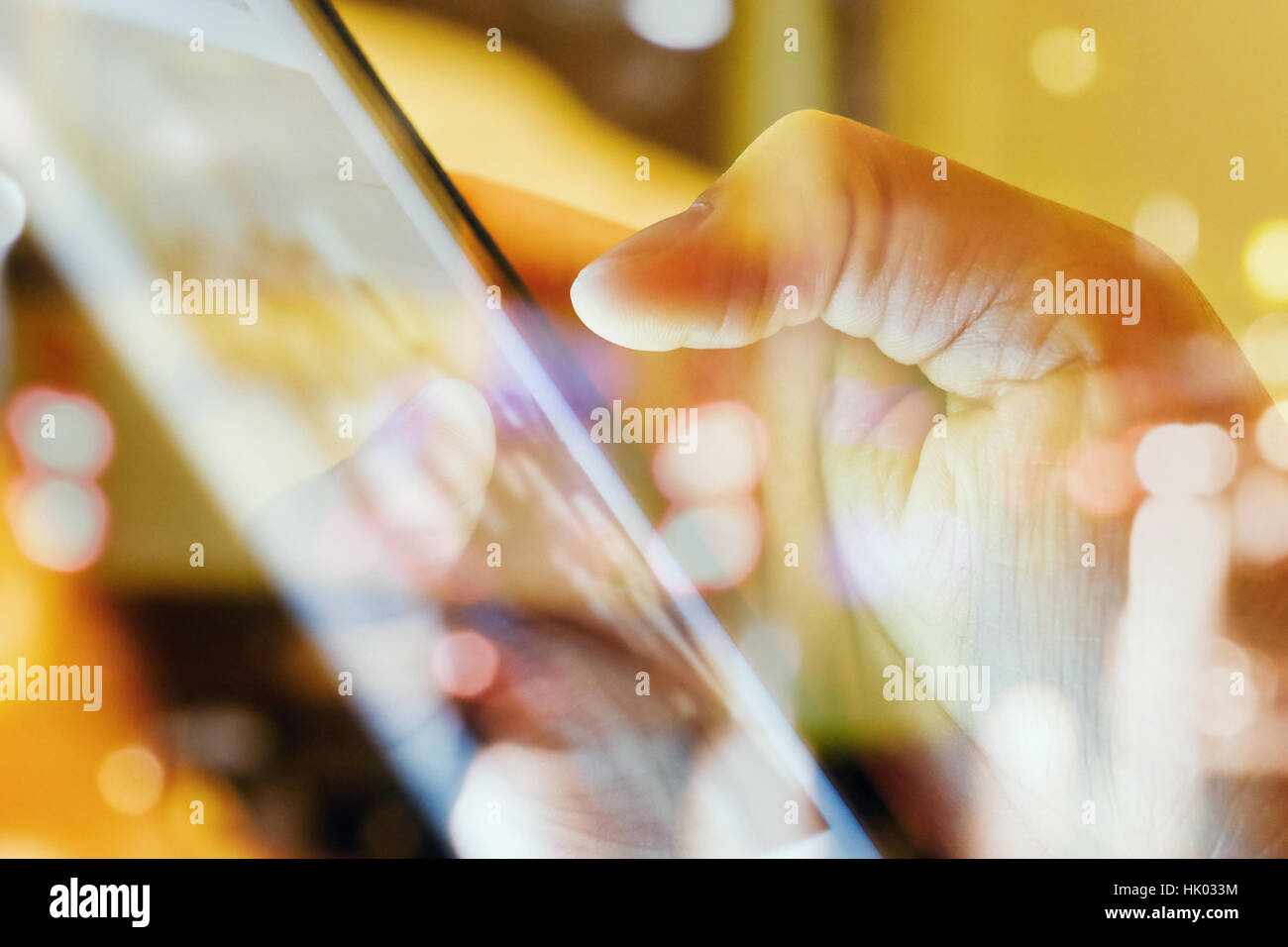 close up of Male fingers touching tablet screen double exposure and defocused city night light background. Stock Photo
