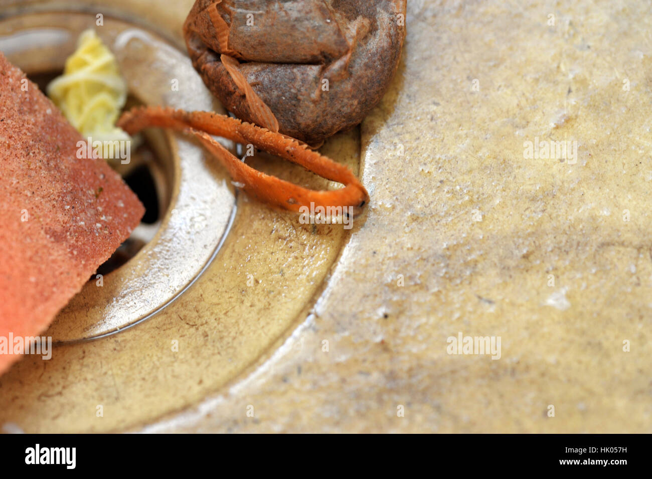 Stained and dirty unhygienic kitchen sink with wash sponge, food waste