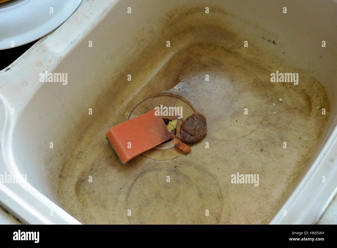 Stained and dirty unhygienic kitchen sink with wash sponge, food wsate