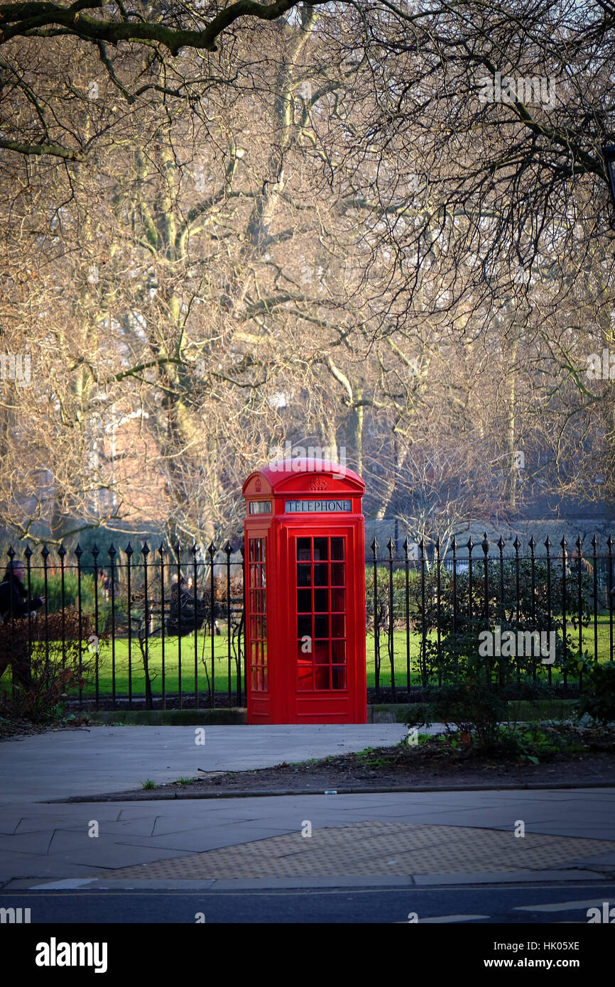 An old fashioned red telephone box stands on a street corner in London