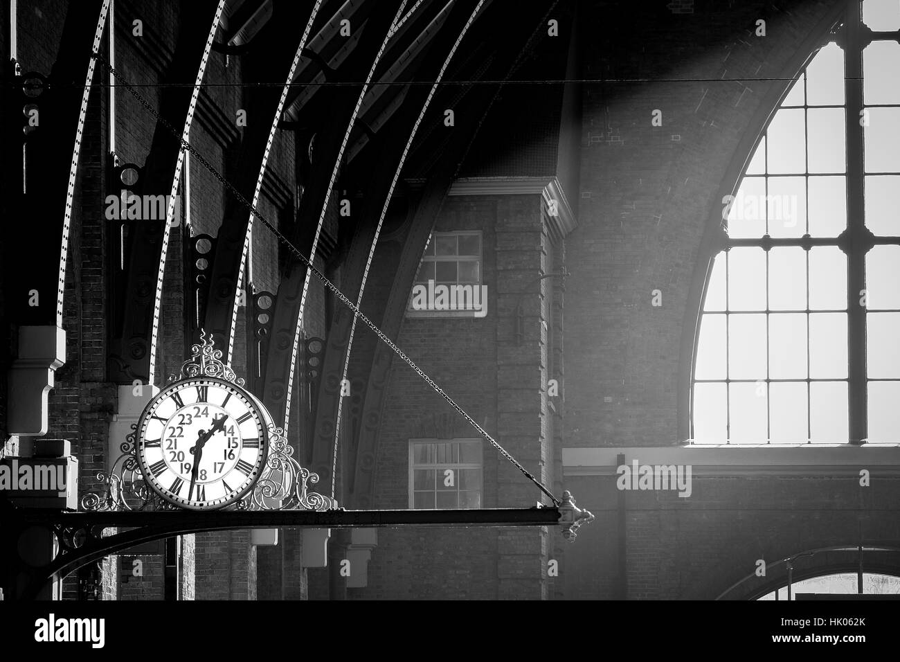An old fashioned clock is lit by a shaft of sunlight Stock Photo