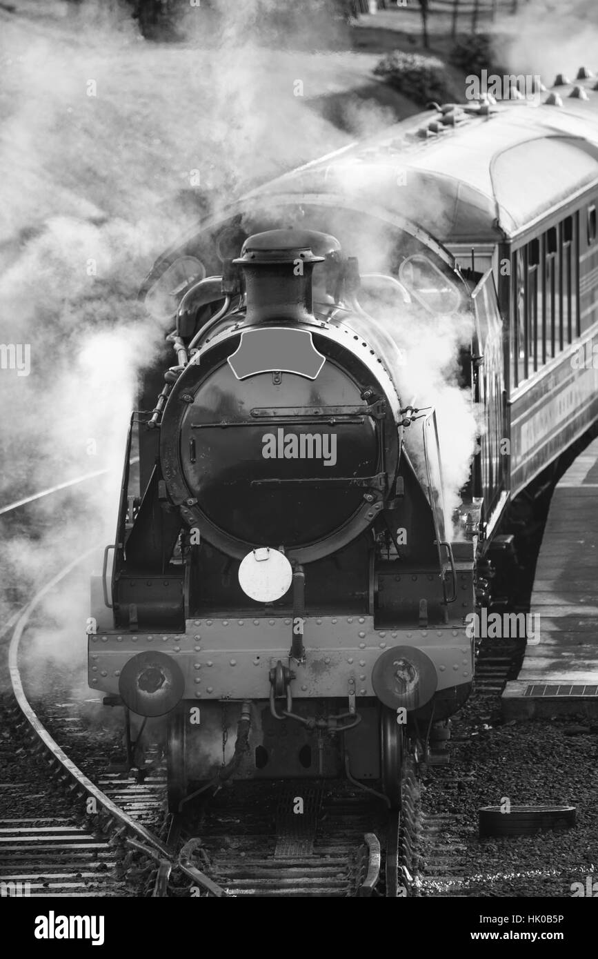 Victorian era steam train engine with full steam in black and white Stock Photo
