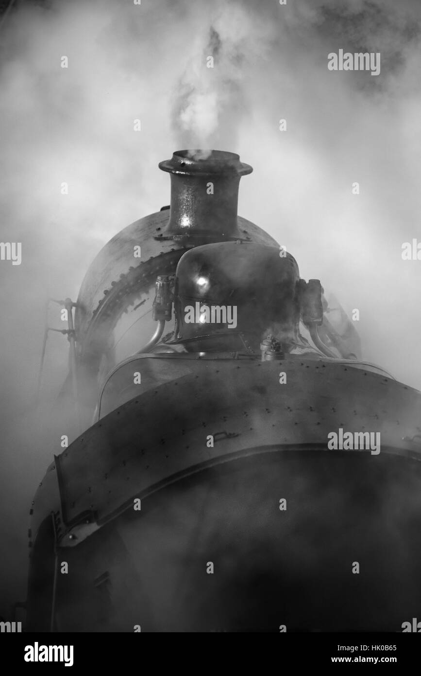 Victorian era steam train engine with full steam in black and white Stock Photo