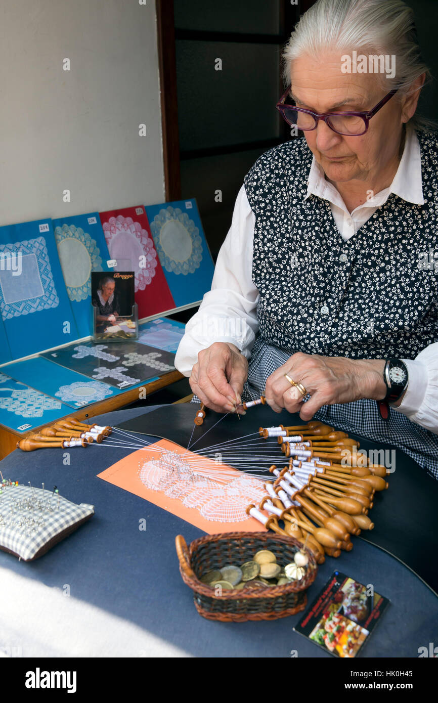Old lady making lace by hand using pins and bobbins, Bruges, West Flanders, Belgium Stock Photo
