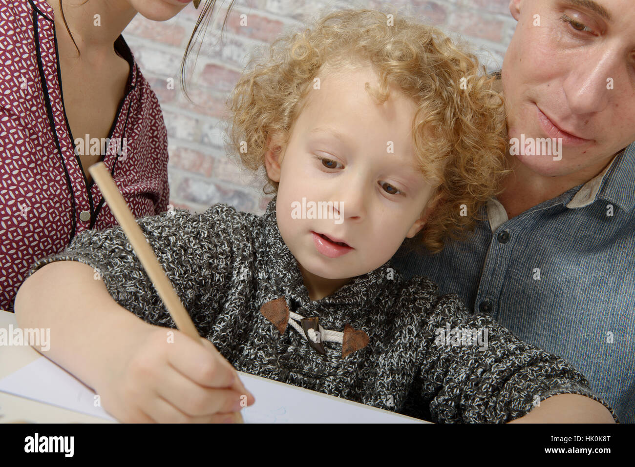 Little Blond Curly Boy Drawing With His Parents Stock Photo