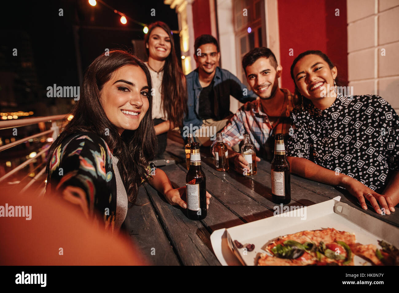 Friends having rooftop party and making a selfie. Young people taking self portrait at party in evening. Stock Photo