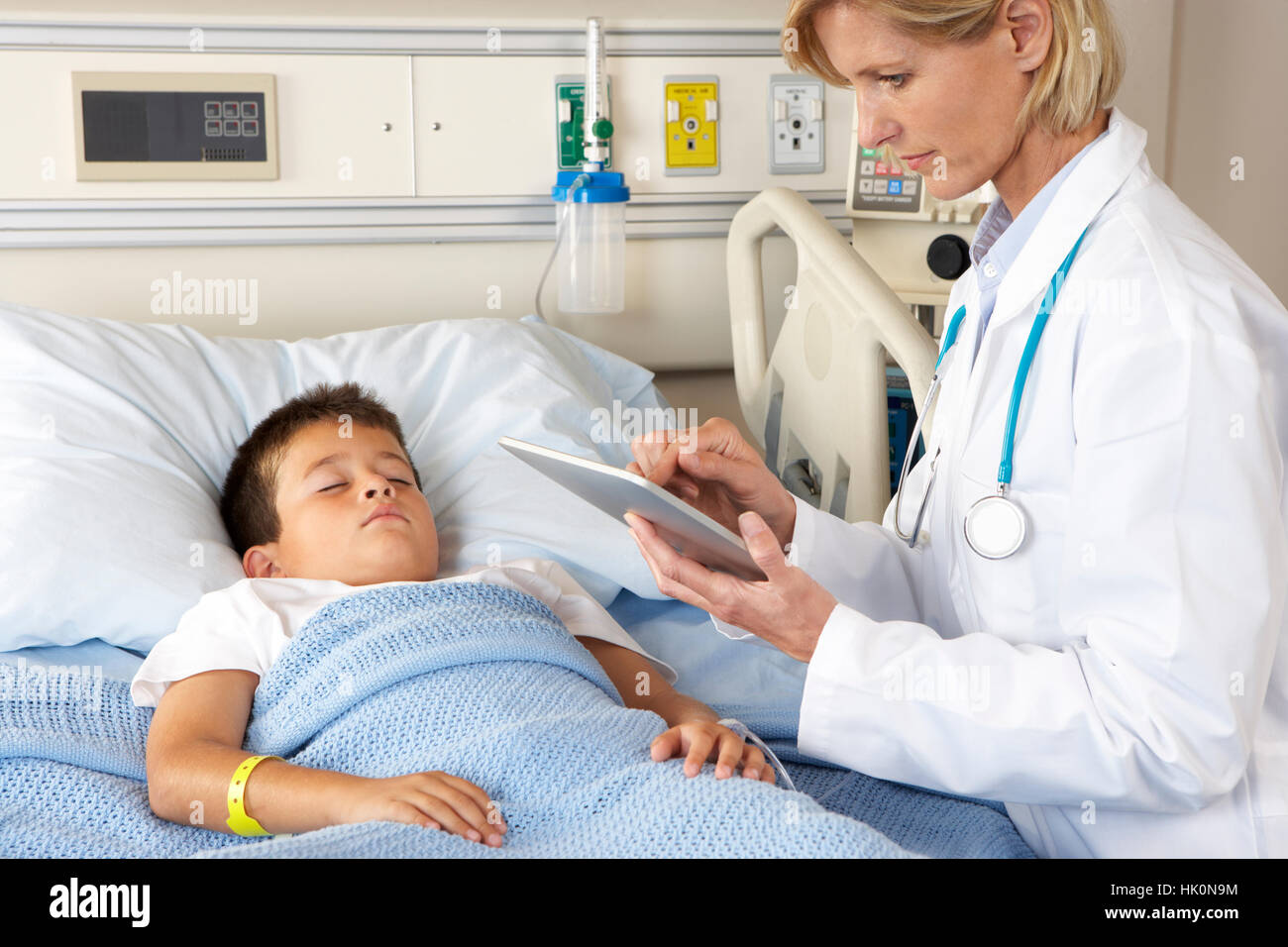 Doctor Using Digital Notepad Whilst Visiting Child Patient Stock Photo