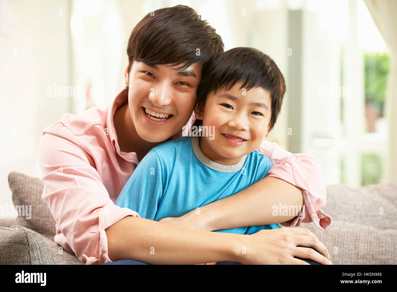 Chinese Father And Son Relaxing On Sofa At Home Stock Photo Alamy