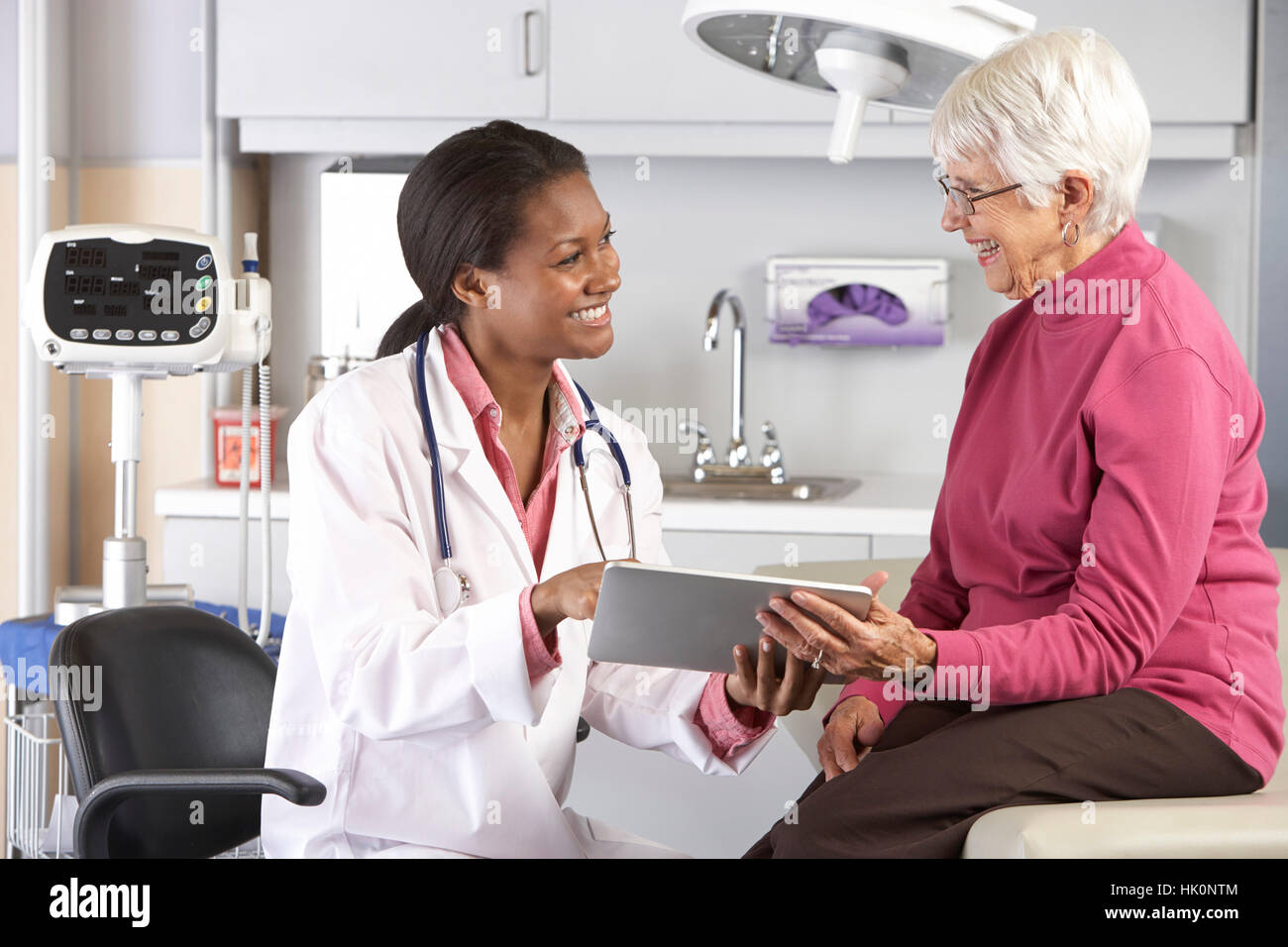 Doctor Discussing Records With Senior Female Patient Stock Photo - Alamy