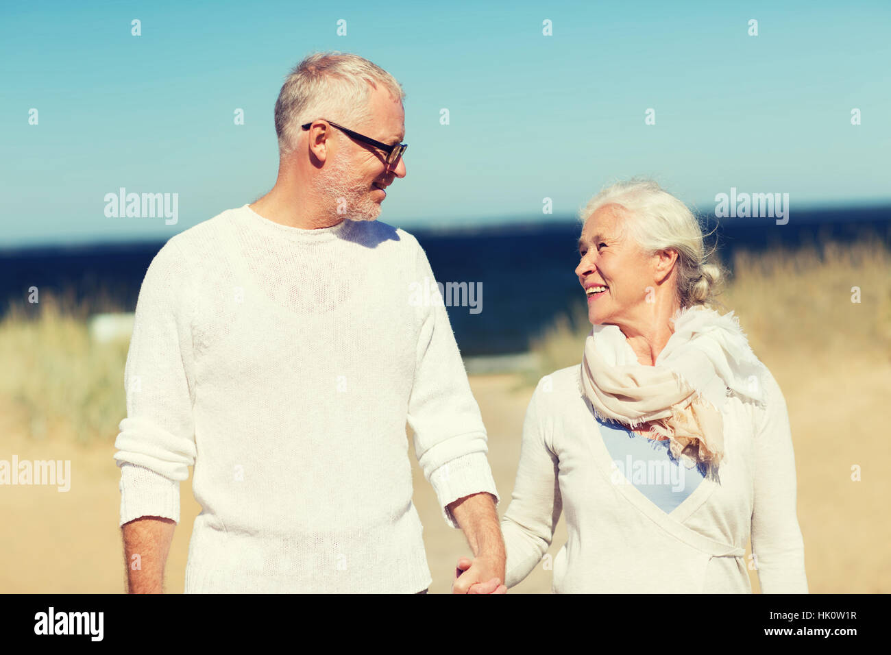 happy senior couple holding hands on summer beach Stock Photo - Alamy