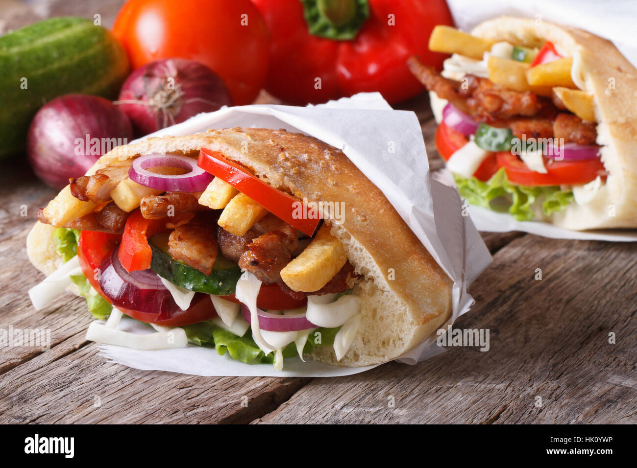 Doner kebab with meat and vegetables in pita bread wrapped in paper  close-up on the table and ingredients horizontal Stock Photo - Alamy